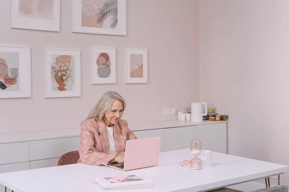 Uśmiechnięta osoba pracująca przy laptopie w jasnym, nowoczesnym biurze.